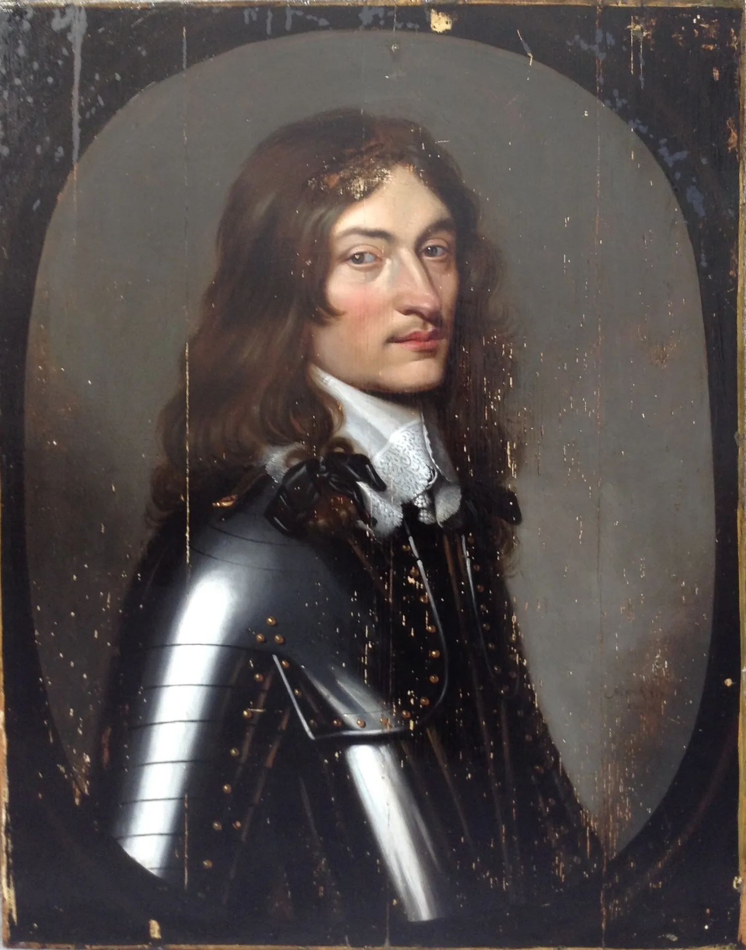 Retrato de caballero con armadura y cuello de encaje en formato oval, pintado sobre tabla, antes de la restauración: pérdidas de color en líneas verticales que siguen la veta de la madera.